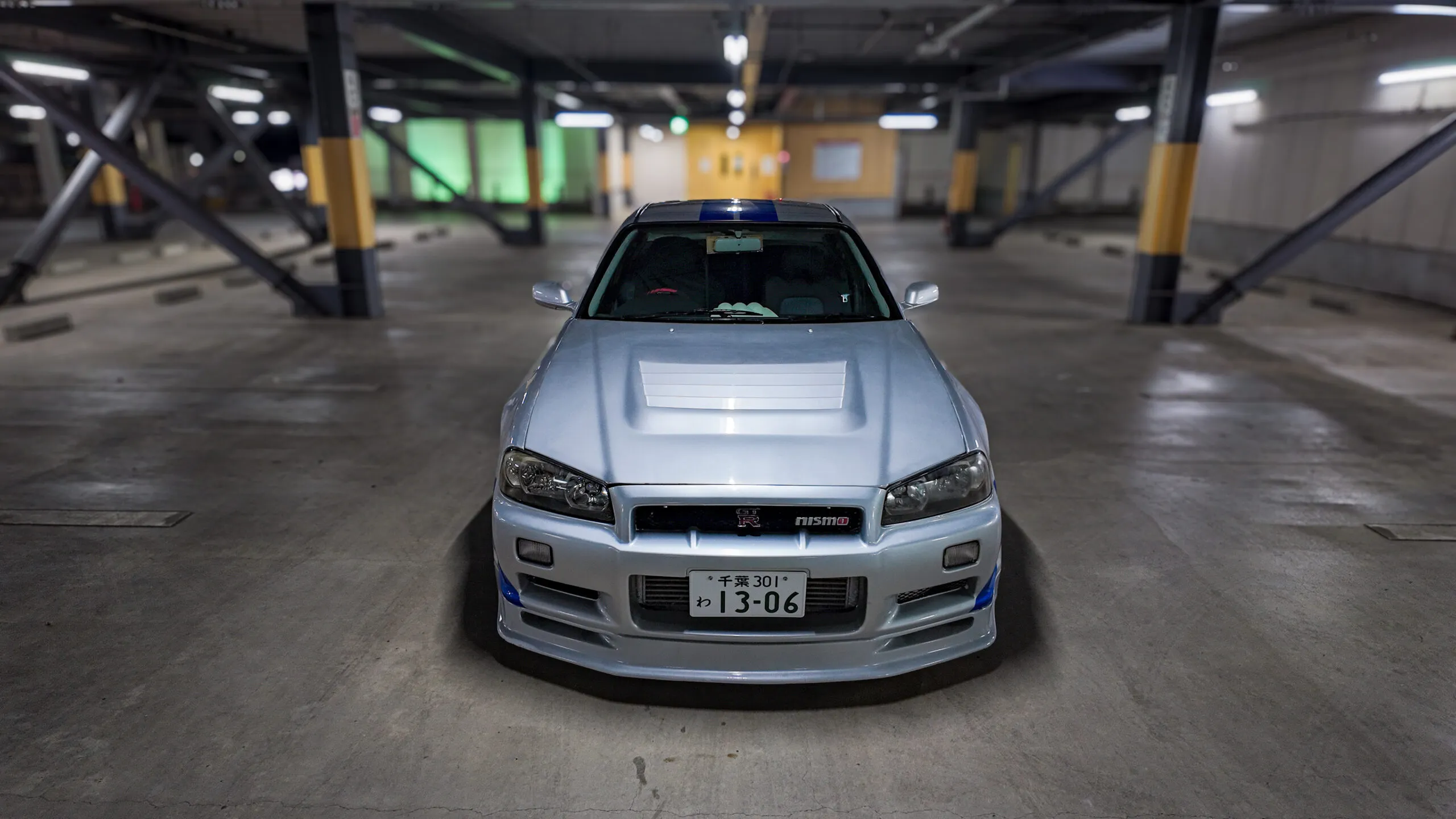 Interior view of a Nissan Skyline GT-R R34 with a custom dashboard, racing steering wheel, and performance meters in the cabin.